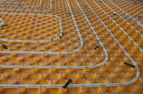 Orange posed Underfloor heating tube in a construction site